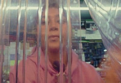 a woman in a pink hoodie behind bars