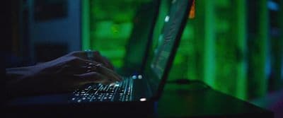 a person typing on a laptop in a dark room