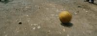 a yellow ball sitting on top of a dirt road