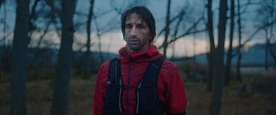 a man in a red jacket standing in a forest