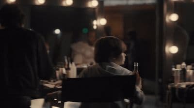 a woman sitting at a table with a bottle of wine
