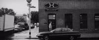 a black and white photo of a car parked in front of a building
