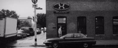 a black and white photo of a car parked in front of a building