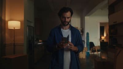 a man standing in a room looking at a cell phone