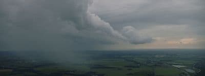 a large cloud is in the sky over a green field