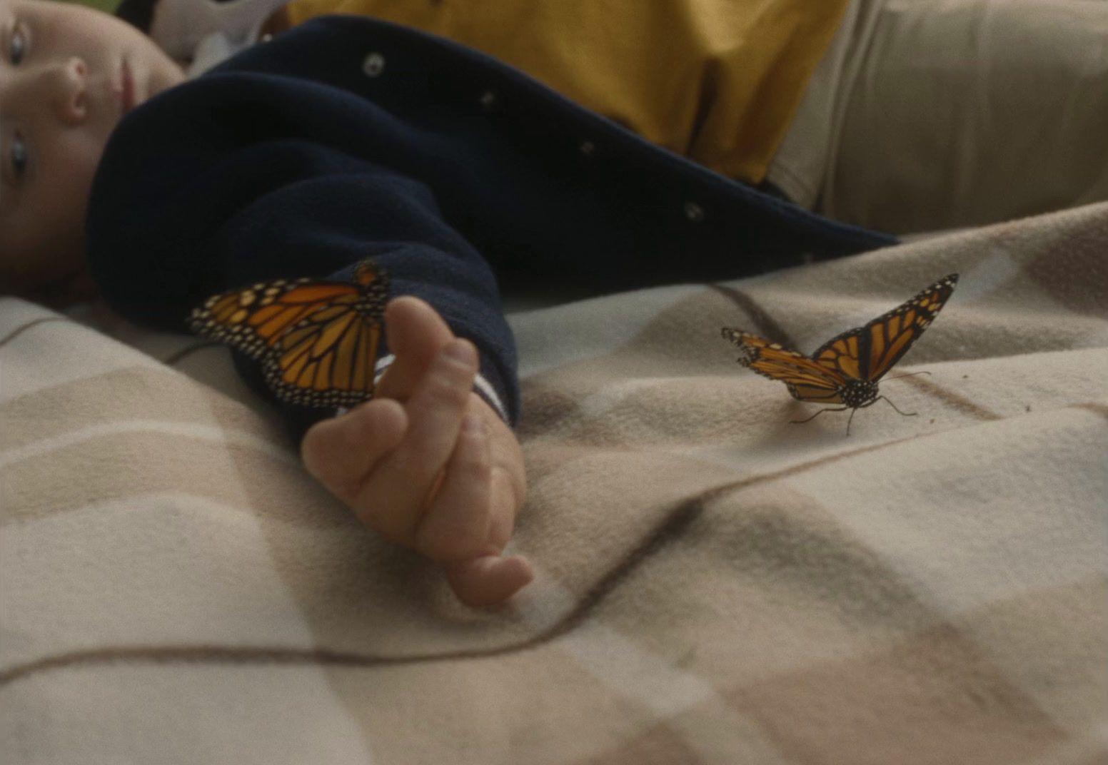 a baby laying on a bed with a butterfly on it