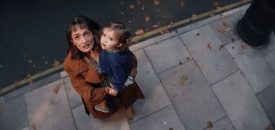 a woman holding a small child on top of a sidewalk