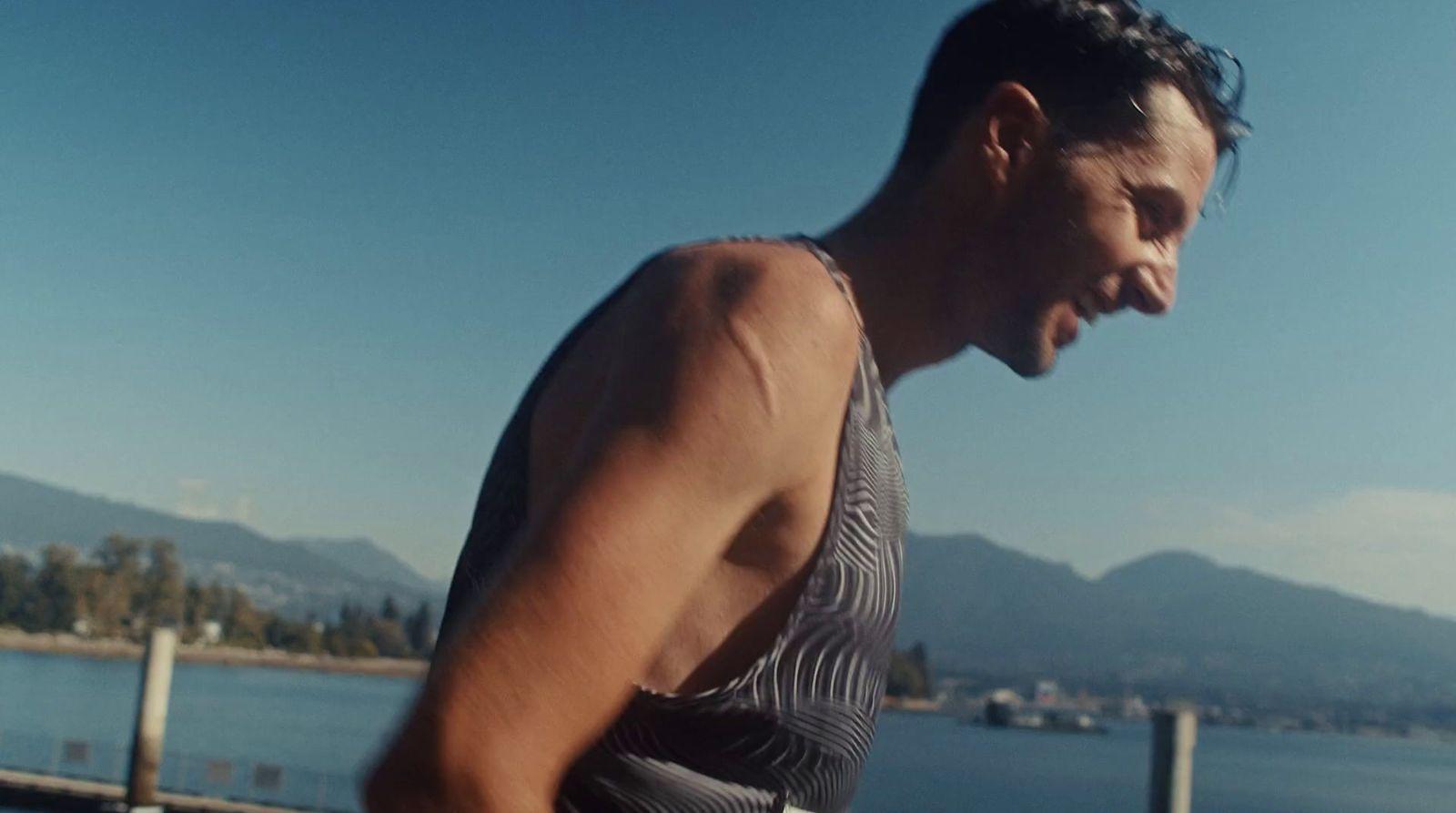 a man in a tank top holding a skateboard