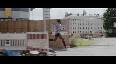 a man running down a street next to a fence