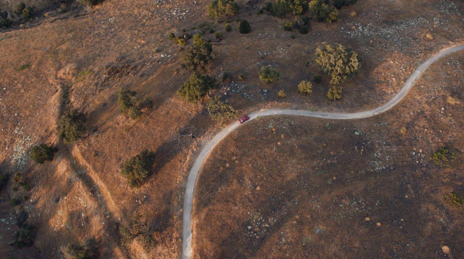 an aerial view of a dirt road in the middle of a field