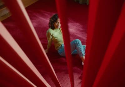 a woman sitting on the floor in front of a red curtain