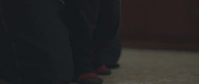 a close up of a person's feet wearing black pants and red socks