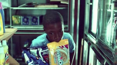 a young boy holding a bag of chips in front of a refrigerator