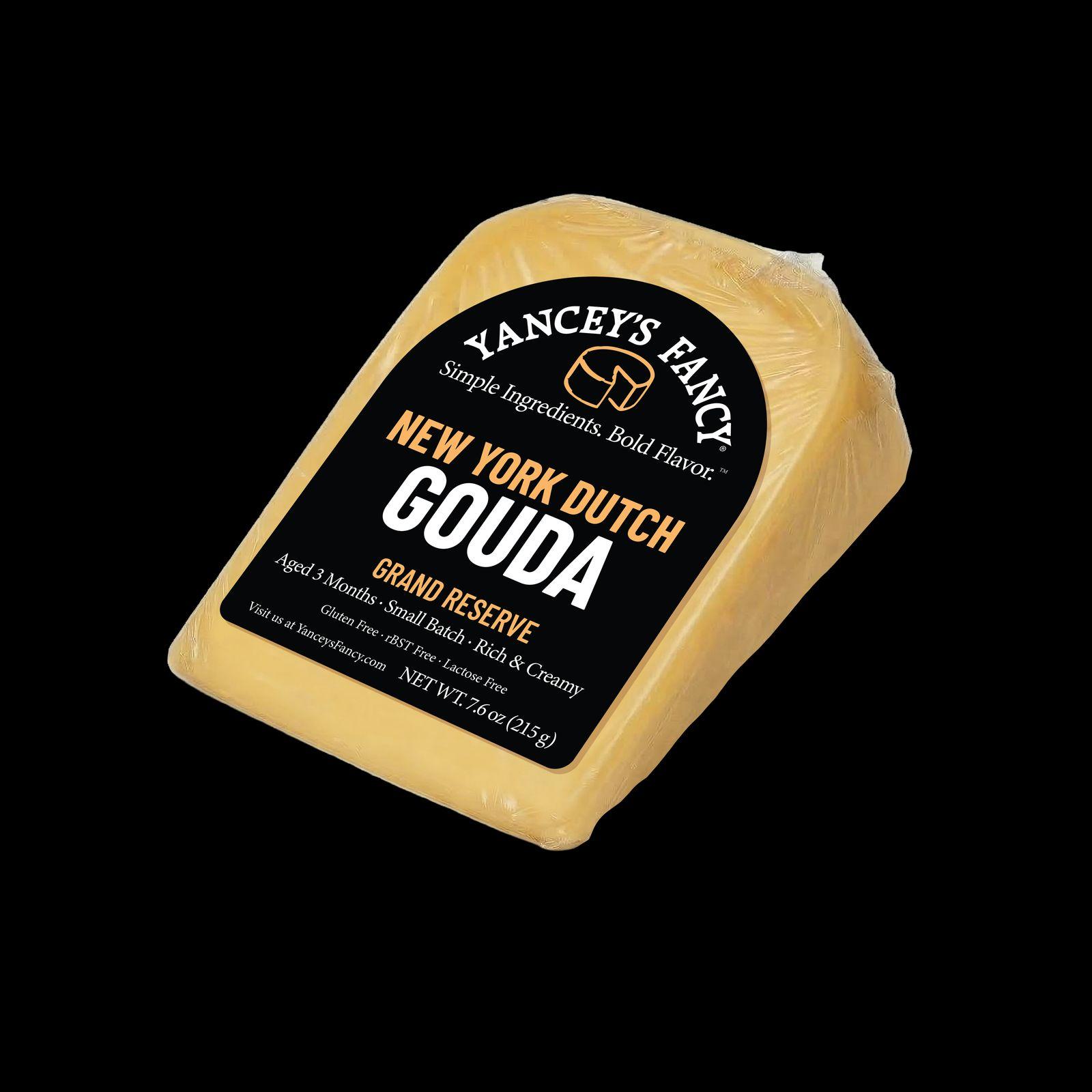 Studio product photo of a golden-yellow wrapped wedge of Yancey’s Fancy New York Dutch Gouda with a black label against a solid black background.