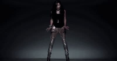 a woman in a black top and gold pants