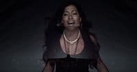 a woman in a black dress with a necklace on