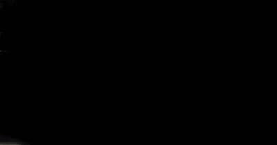 a man in a suit and tie standing in front of a black background