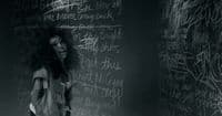 a woman standing in front of a blackboard with writing on it