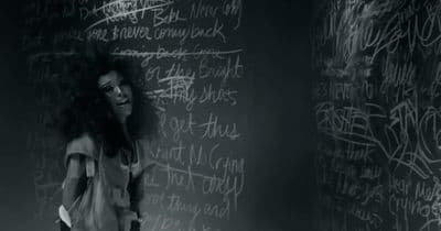 a woman standing in front of a blackboard with writing on it