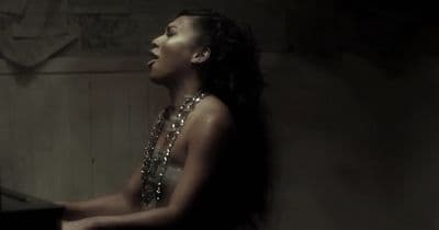 a woman sitting at a piano in a dark room