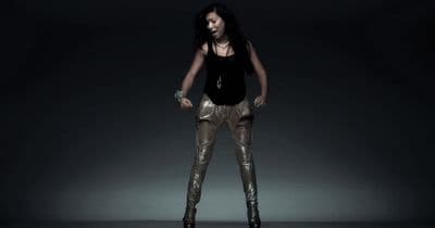 a woman standing in a dark room with her hands on her hips