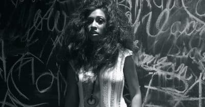 a woman standing in front of a wall covered in graffiti