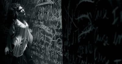 a woman standing in front of a wall covered in graffiti