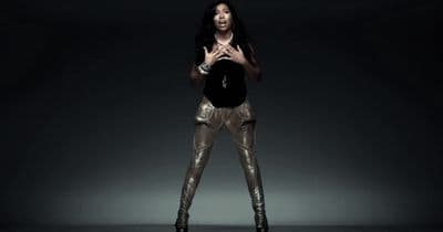 a woman standing in a dark room with her hands together