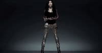 a woman in a black top and gold pants