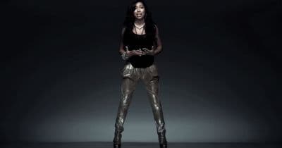 a woman in a black top and gold pants