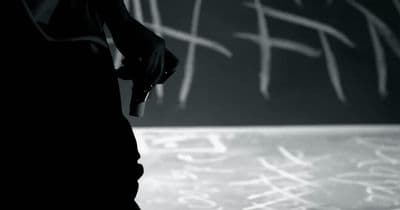 a black and white photo of someone writing on a chalkboard