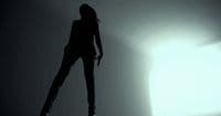 a woman standing in the shadows of a room
