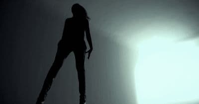 a woman standing in the shadows of a room