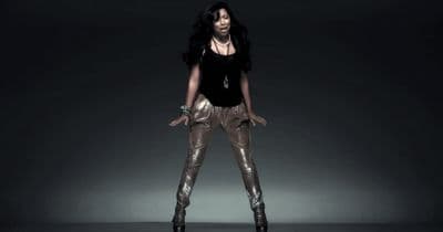 a woman in a black top and gold pants
