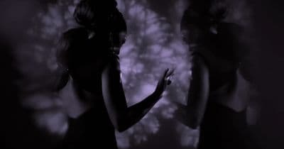 a woman standing in front of a wall in a dark room