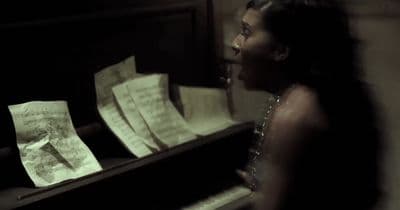 a woman standing next to a piano with sheet music on it