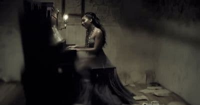 a woman sitting at a piano in a dark room