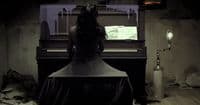 a woman sitting at a piano in a dark room