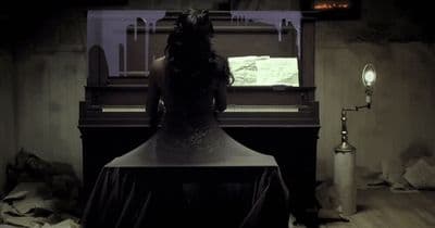 a woman sitting at a piano in a dark room