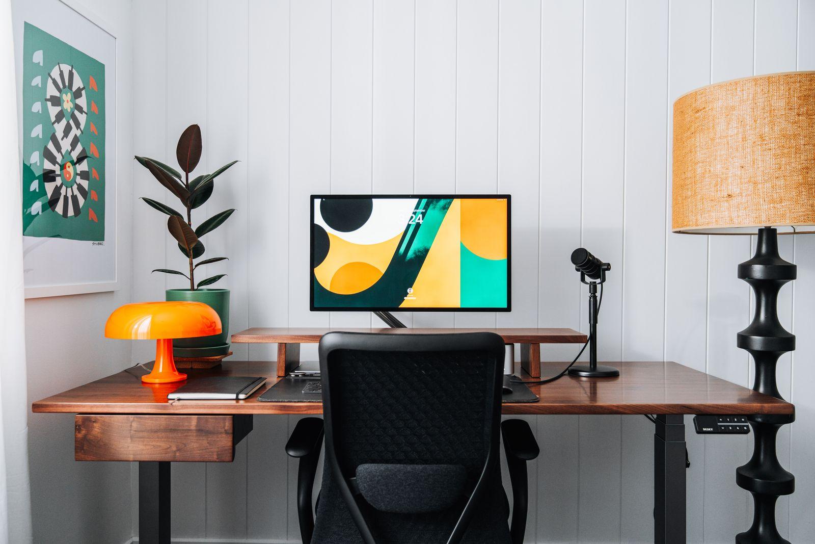 a desk with a computer and a lamp on it