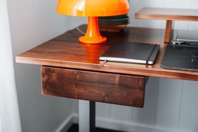 a desk with a laptop and a lamp on it