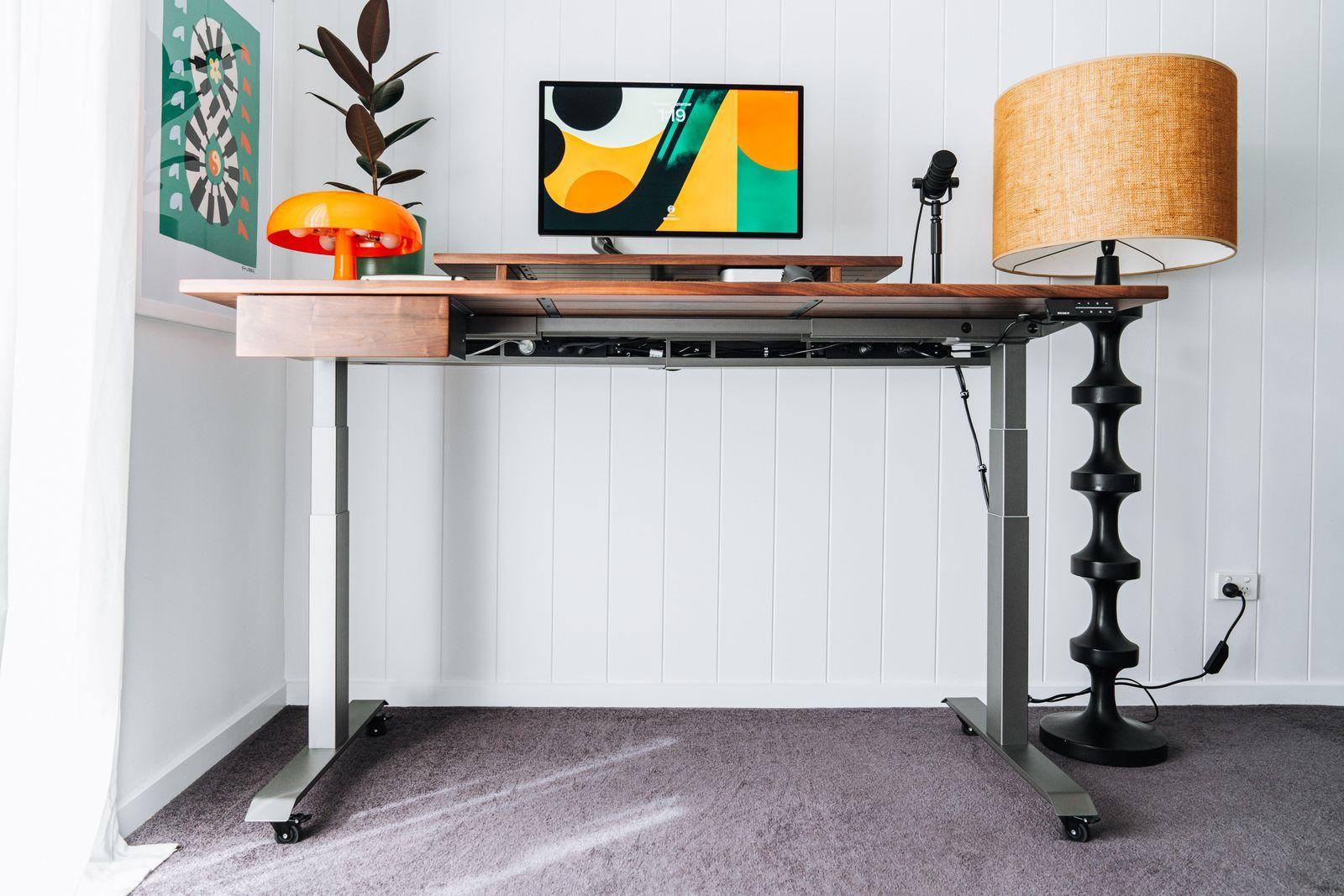 a desk with a lamp and a painting on the wall