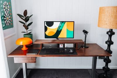 a desk with a computer and a lamp on it