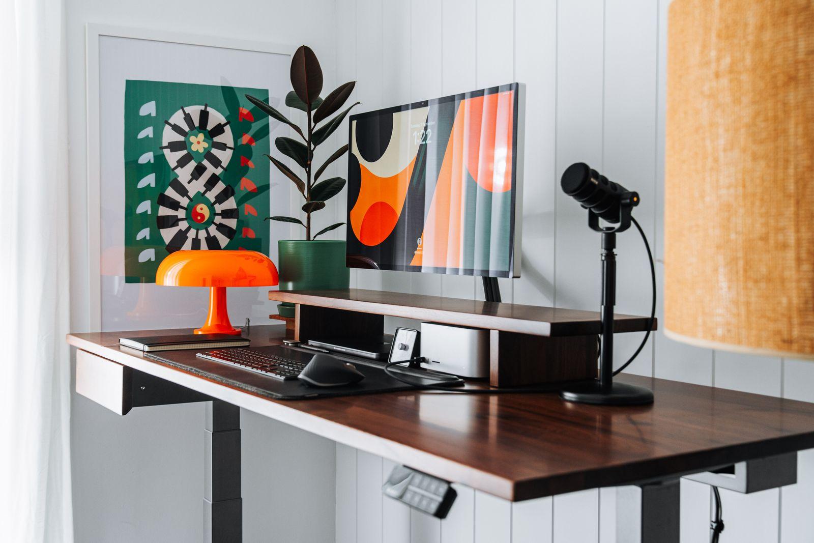 a desk with a lamp and a painting on the wall