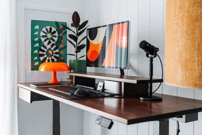 a desk with a lamp and a painting on the wall