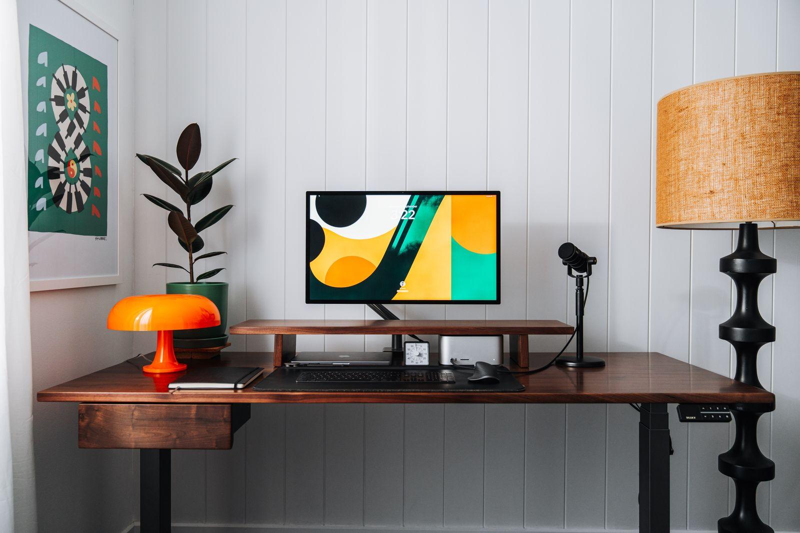 a desk with a computer monitor and a lamp on it