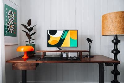 a desk with a computer monitor and a lamp on it