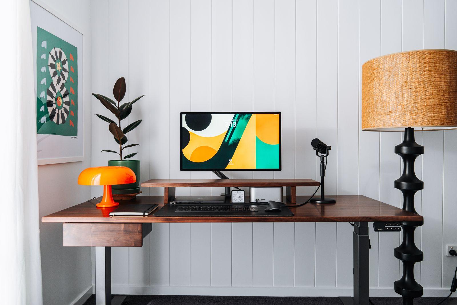 a desk with a computer and a lamp on it