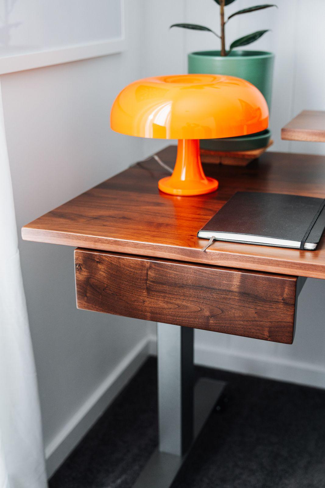 a desk with a laptop and a lamp on it