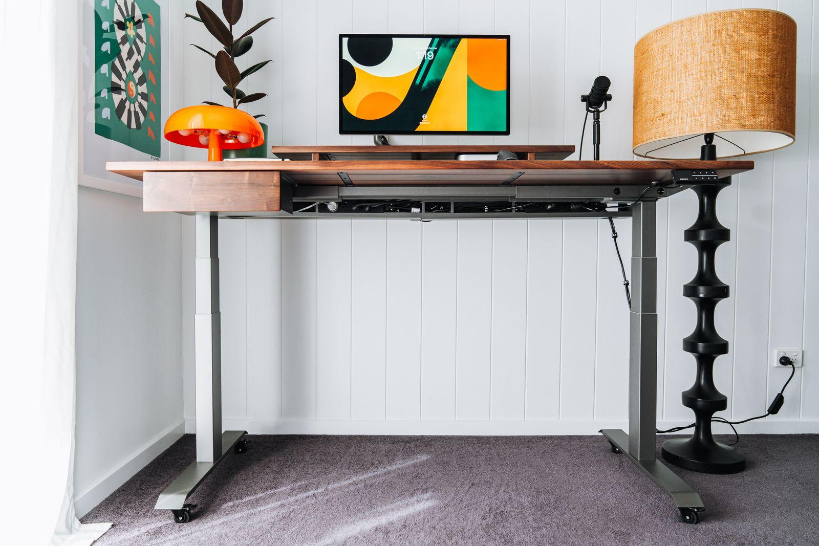 a desk with a lamp and a painting on the wall